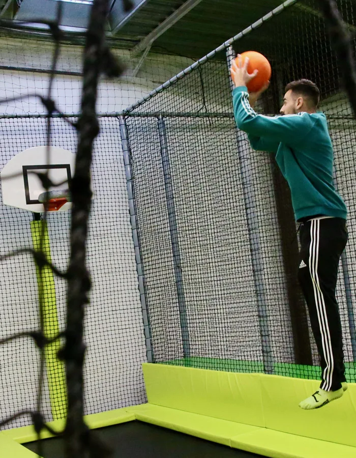 Joueur en suspension au-dessus du trampoline, ballon levé vers le panier