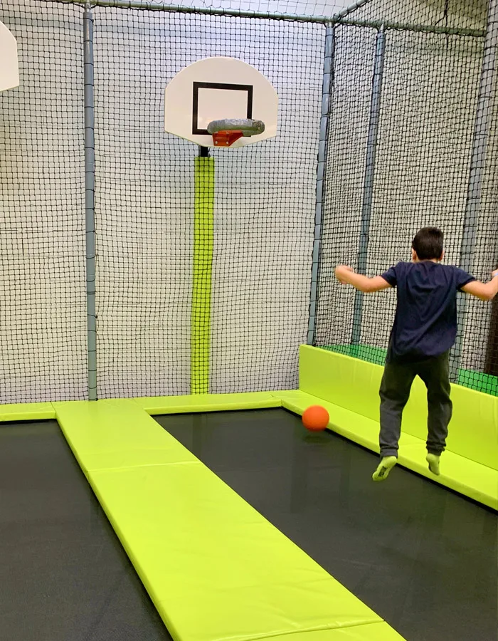 Enfant s’élançant sur le trampoline, ballon à ses pieds