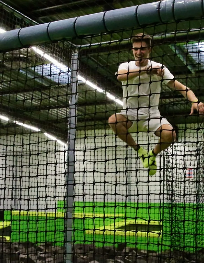 Joueur suspendu au filet de la cage, jambes repliées