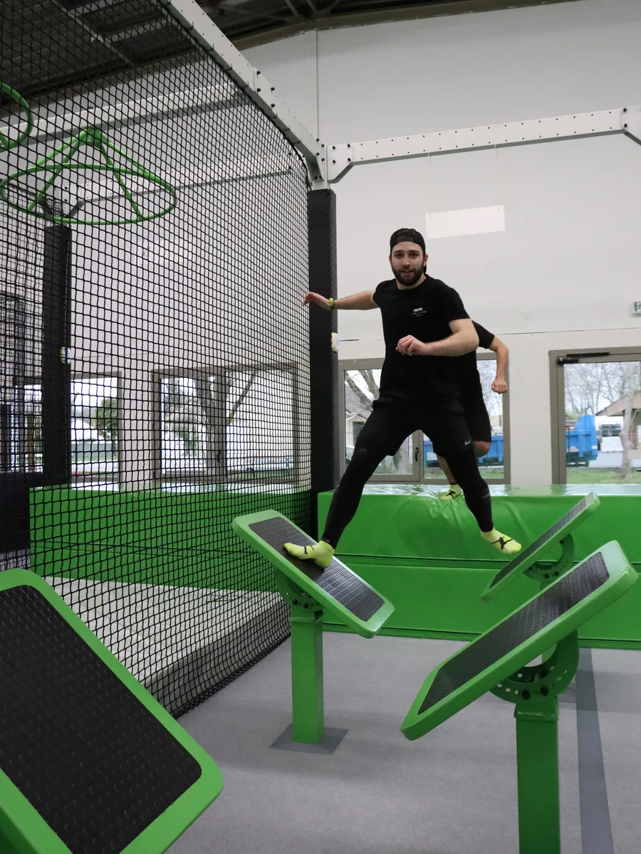 Participant franchissant les plateformes inclinées du parcours Ninja Warrior