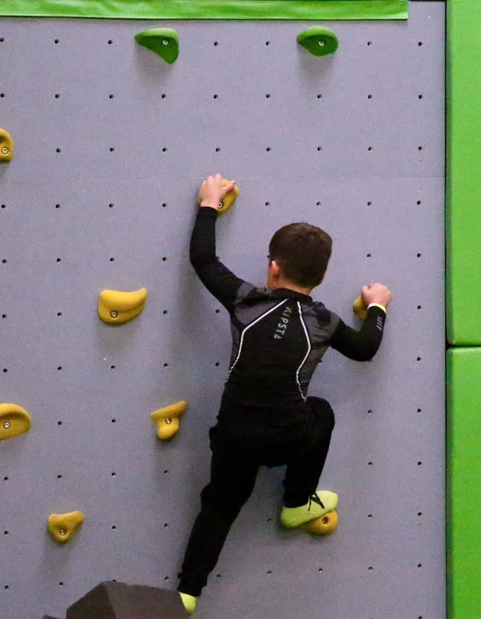 Grimpeur en progression sur les prises jaunes du mur