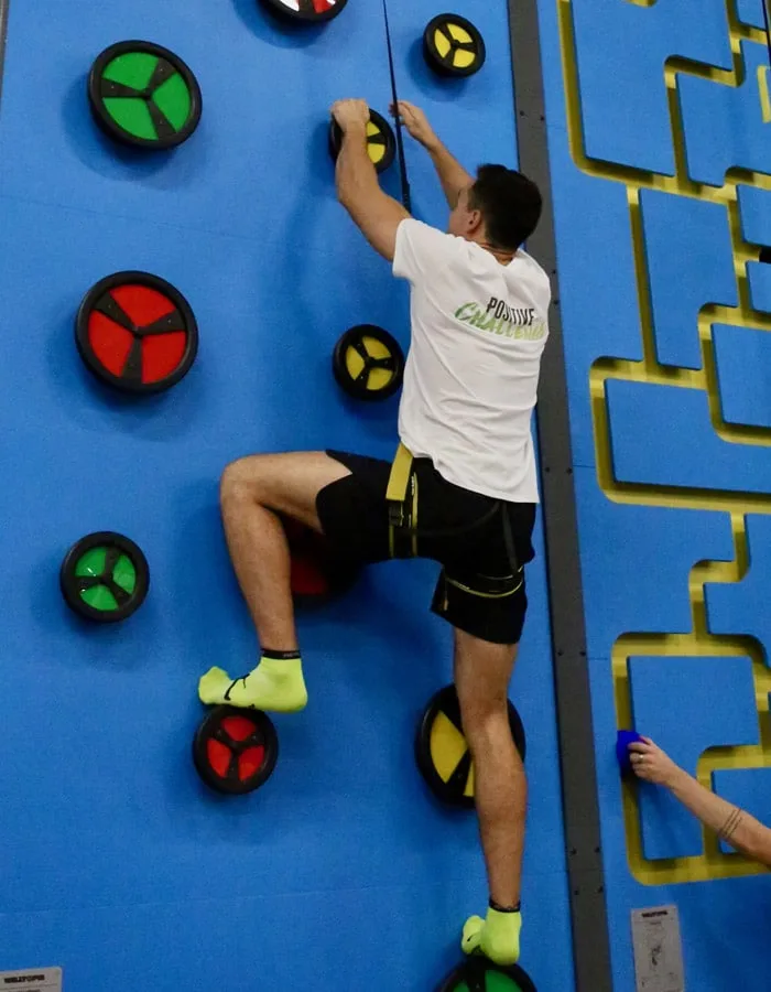 Grimpeur en t‑shirt Positive Challenge sur le mur d’escalade du parc