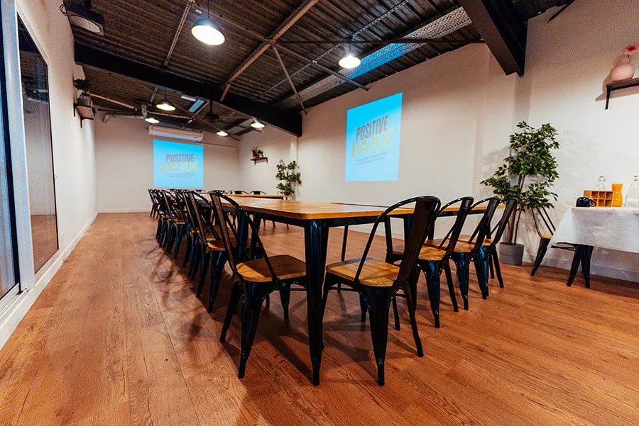 Salle de séminaire, longue table et chaises face à l’écran