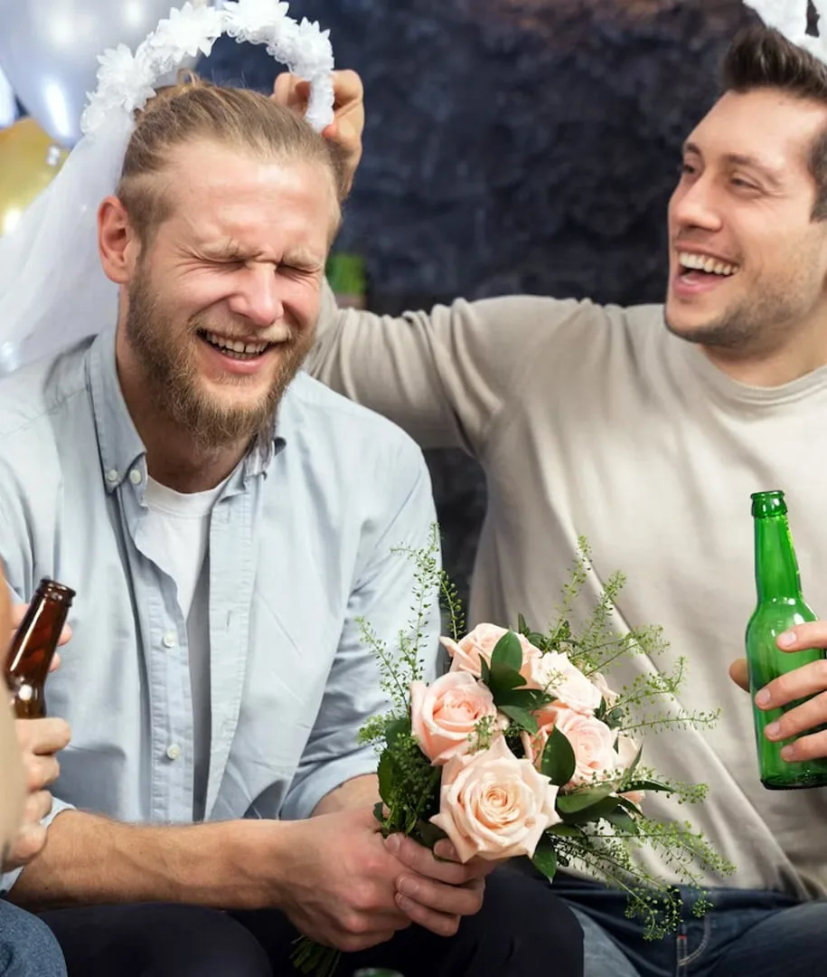 Le futur marié coiffé d’un voile, entouré de ses amis et d’un bouquet de roses