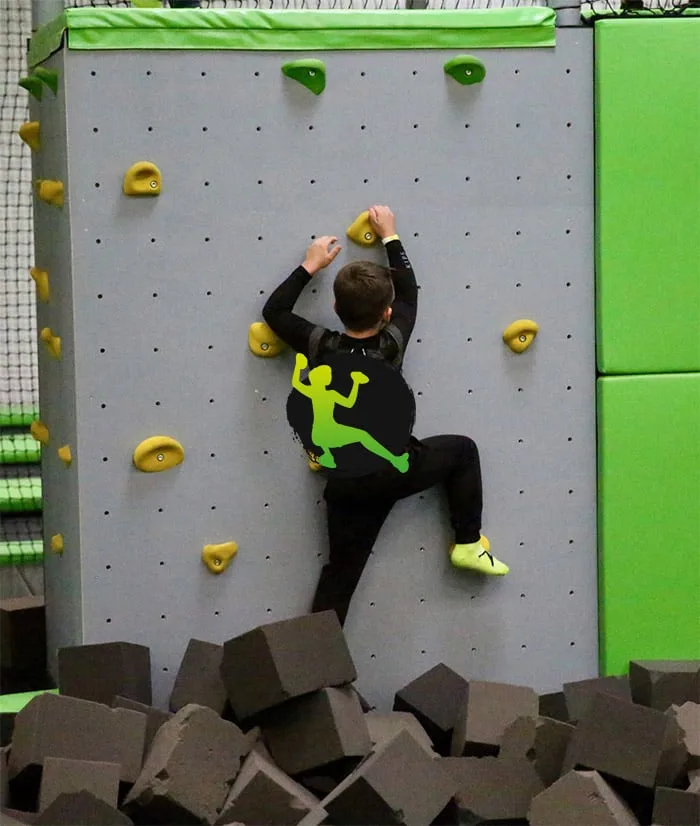 Grimpeur sur le mur d’escalade surplombant la fosse à mousse