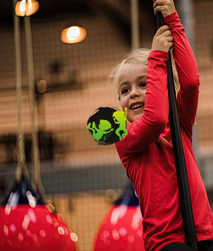 Petite fille souriante agrippée à un mât du mini park