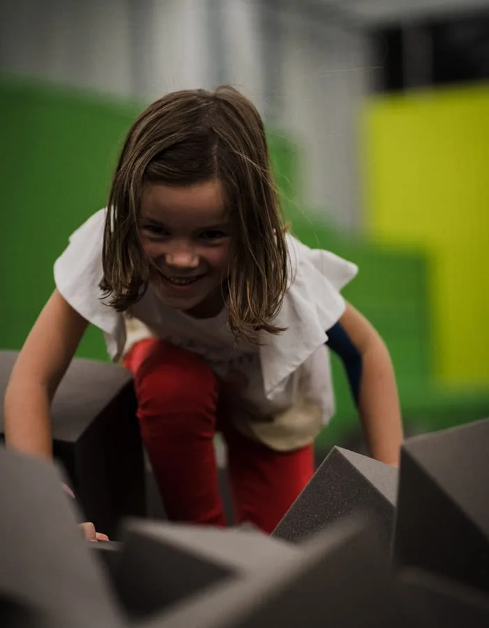 Enfant riant en escaladant les cubes de mousse