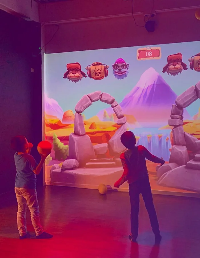 Deux enfants visent les cibles d’un paysage animé projeté sur le mur