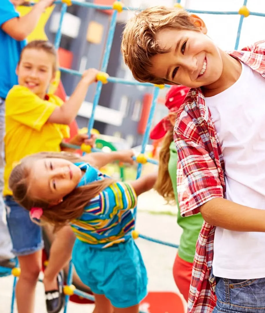 Enfants riant, accrochés à une structure de jeux à cordes
