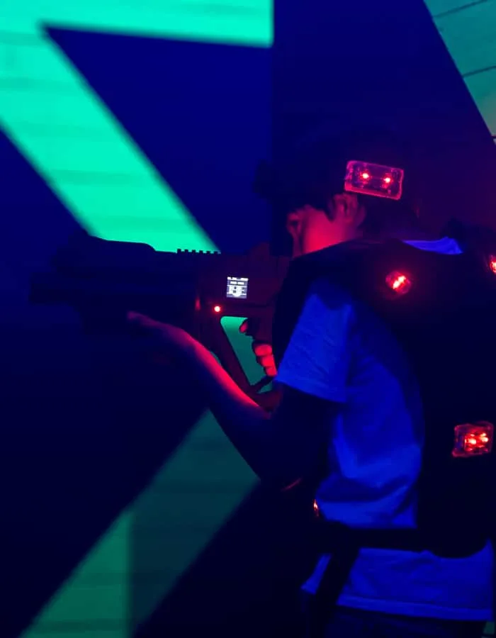 Enfant en gilet lumineux visant dans l’arène du Laser Game