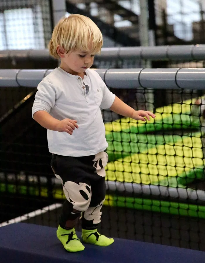 Jeune enfant en équilibre au bord d’un trampoline, chaussettes antidérapantes aux pieds