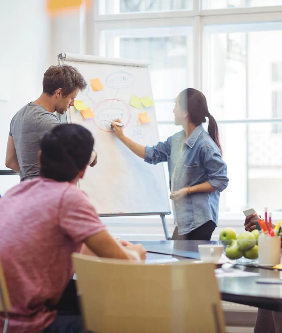 Collaborateurs réunis autour d’un paperboard couvert de post-it pendant un atelier