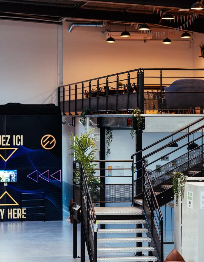 Escalier menant à la mezzanine, plantes et suspensions au-dessus du hall