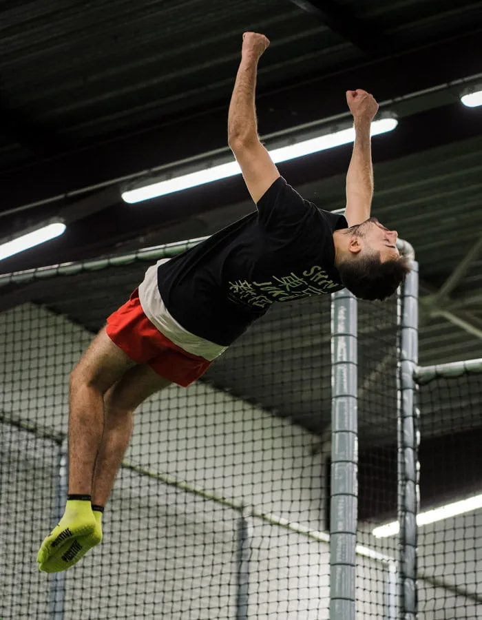 Jumper en salto arrière, poings serrés, au-dessus du trampoline