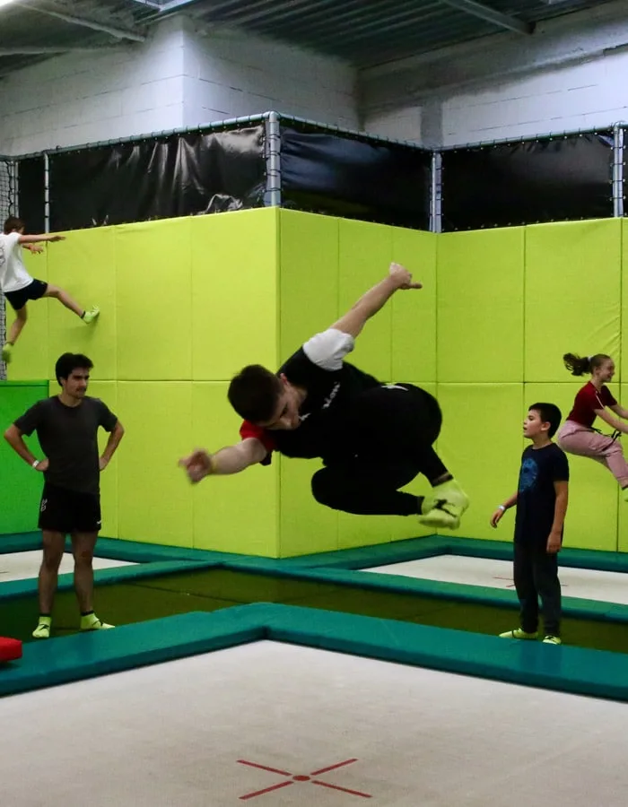 Figure sur le grand trampoline pro, sous le regard des autres jumpers